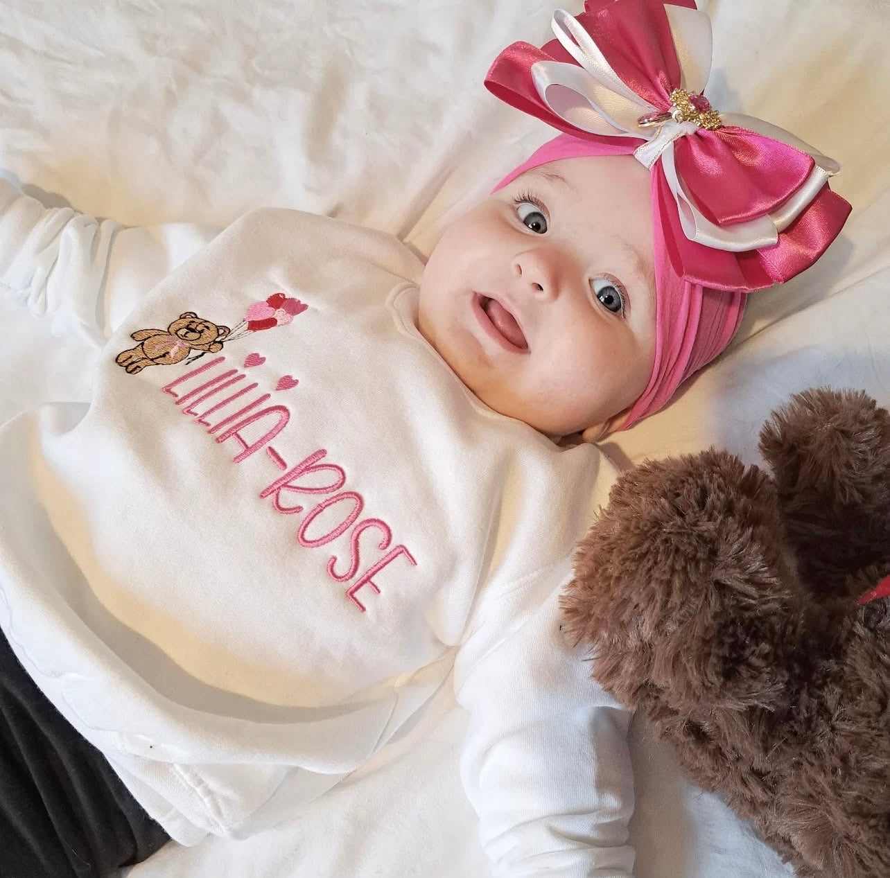 Baby girl wearing White sweatshirt with a bear holding heart balloons with child’s name embroidered on the front