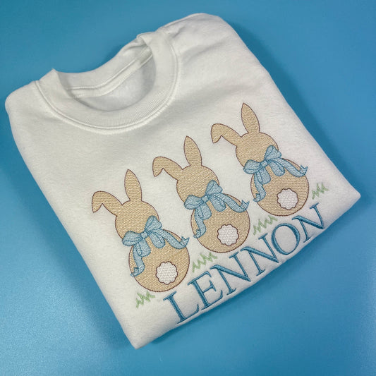 3 bunniess embroidered on a sweatshirt with blue bows and child’s name