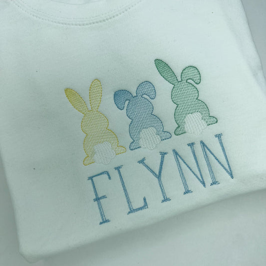 Close up of embroidered bunnies in lemon blue and green