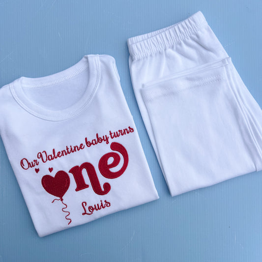 White t-shirt and pants with red text and heart design on a blue background