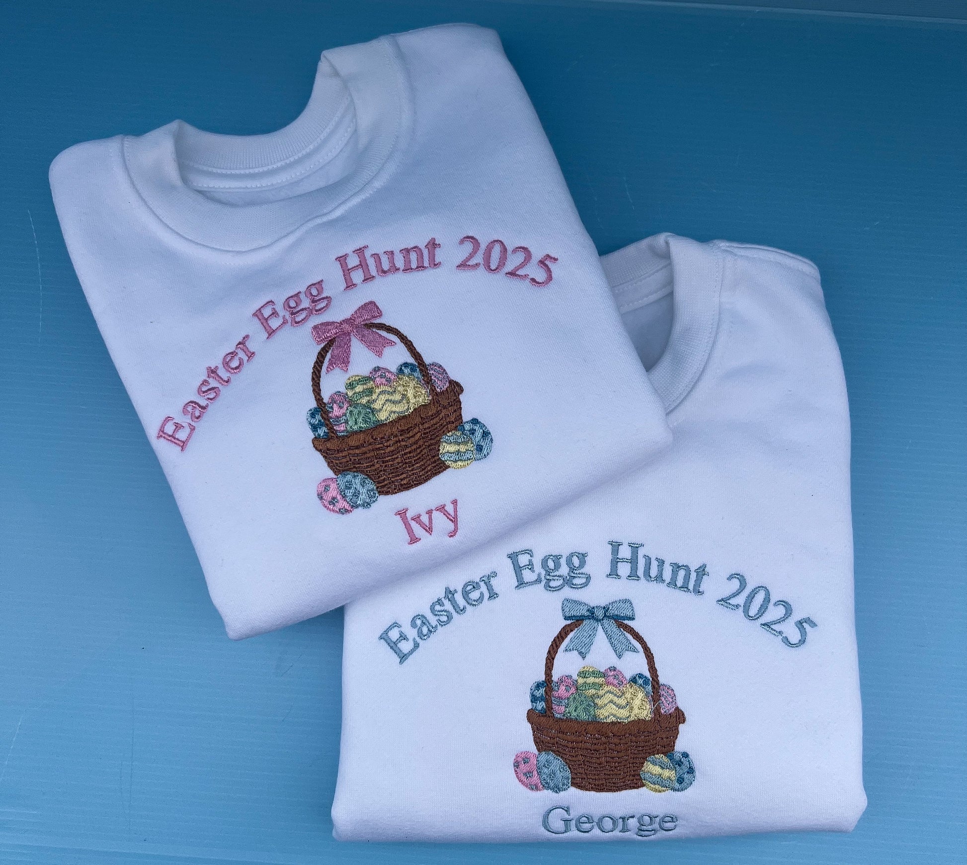Two folded white sweatshirts with Easter-themed designs and text on a blue background.