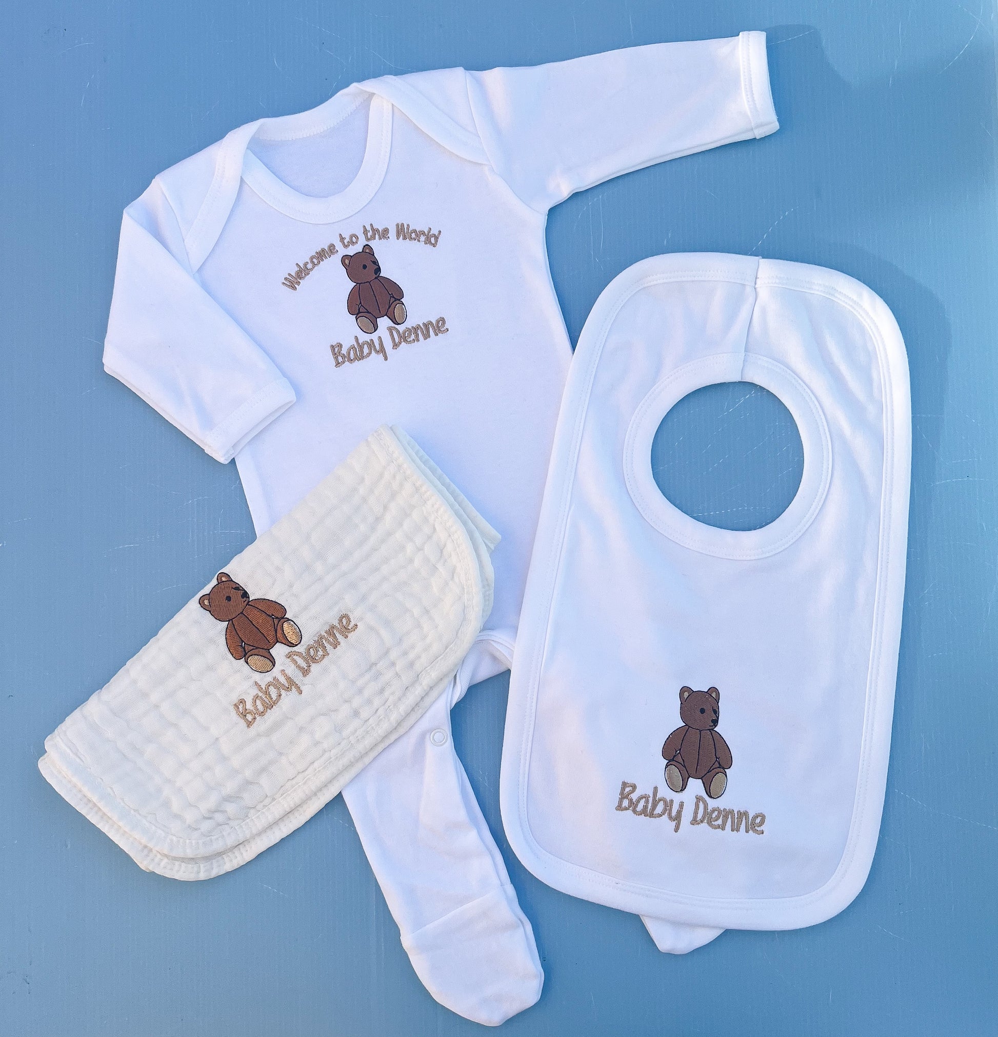 Baby clothing set with bib, onesie, and burp cloth on a blue background