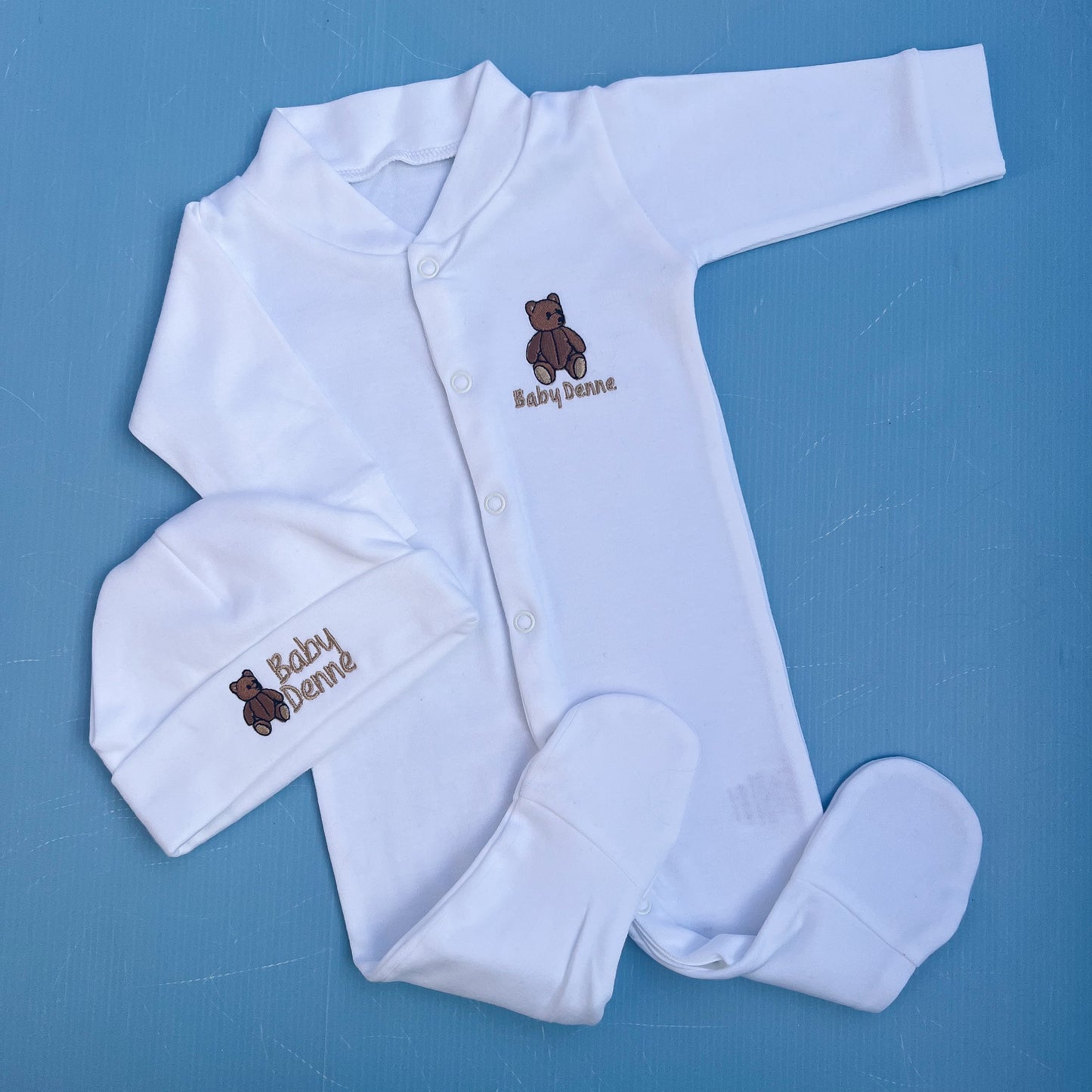 White baby outfit with embroidered teddy bear and 'Baby Bernie' text on a blue background