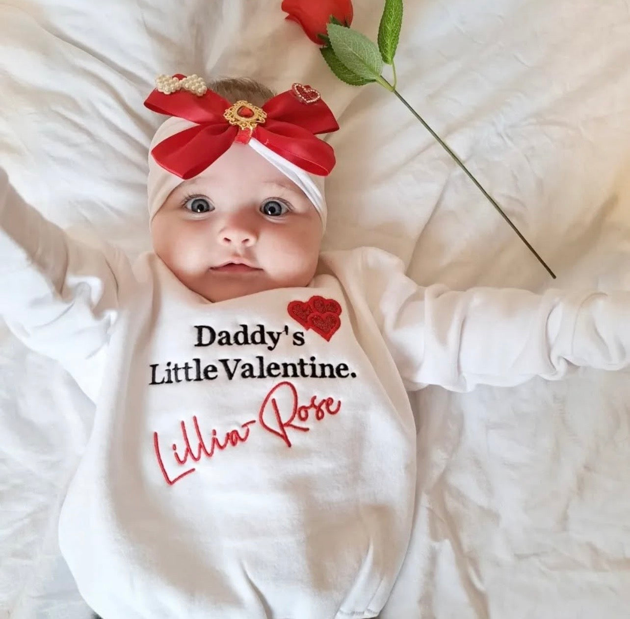 Baby wearing a Daddy's Little Valentine sweatshirt with a red bow and rose.