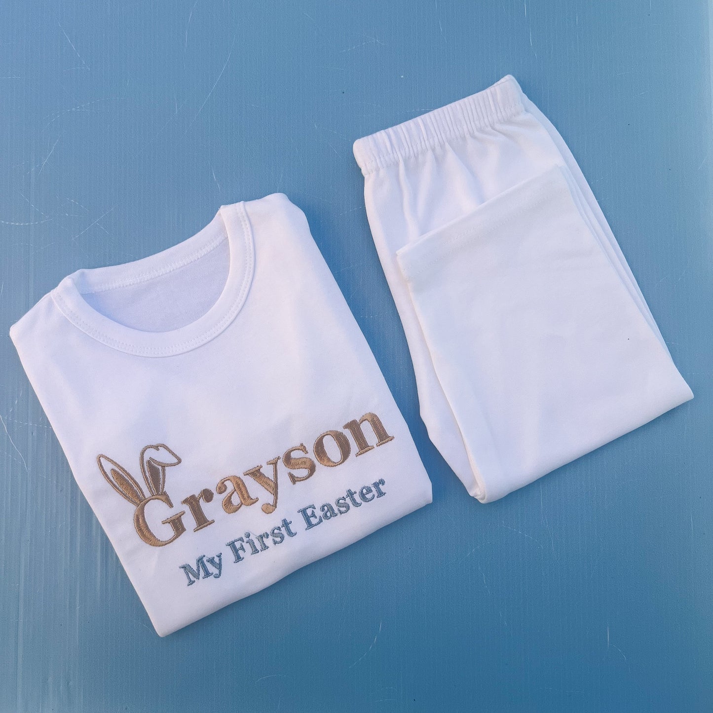 White pyjamas with Grayson first Easter embroidered on with bunny ears 