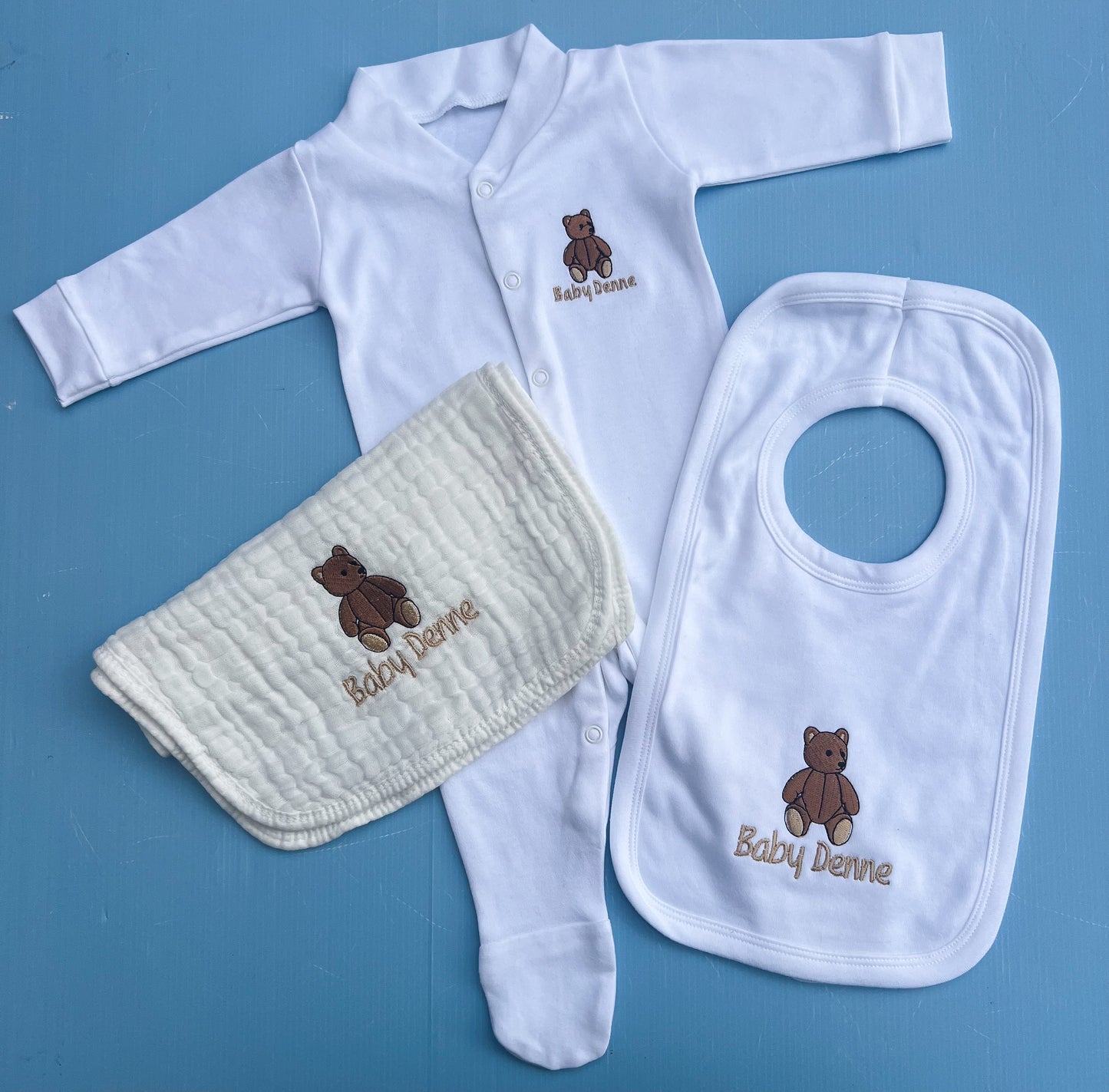 Baby clothing set with bib, shirt, and pants on a blue background