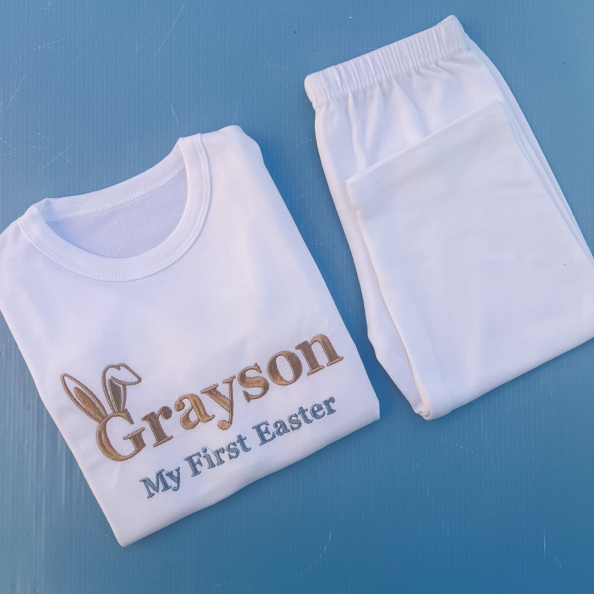 White pyjamas with Grayson first Easter embroidered on with bunny ears 