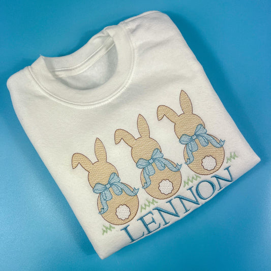 3 bunniess embroidered on a sweatshirt with blue bows and child’s name 