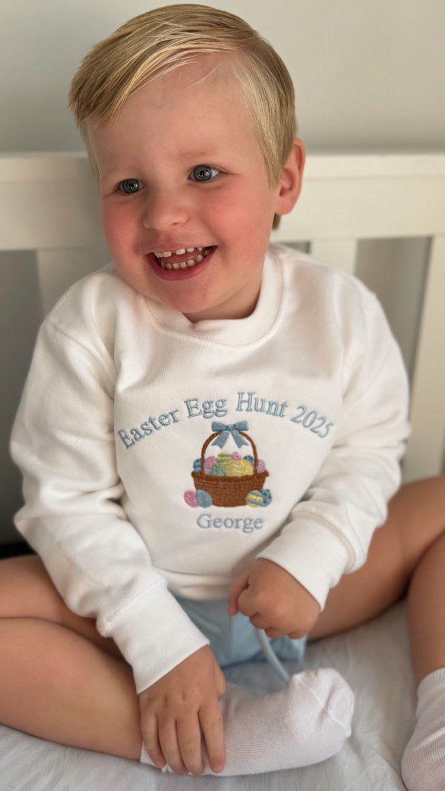 Child wearing a white sweatshirt with Easter design and text
