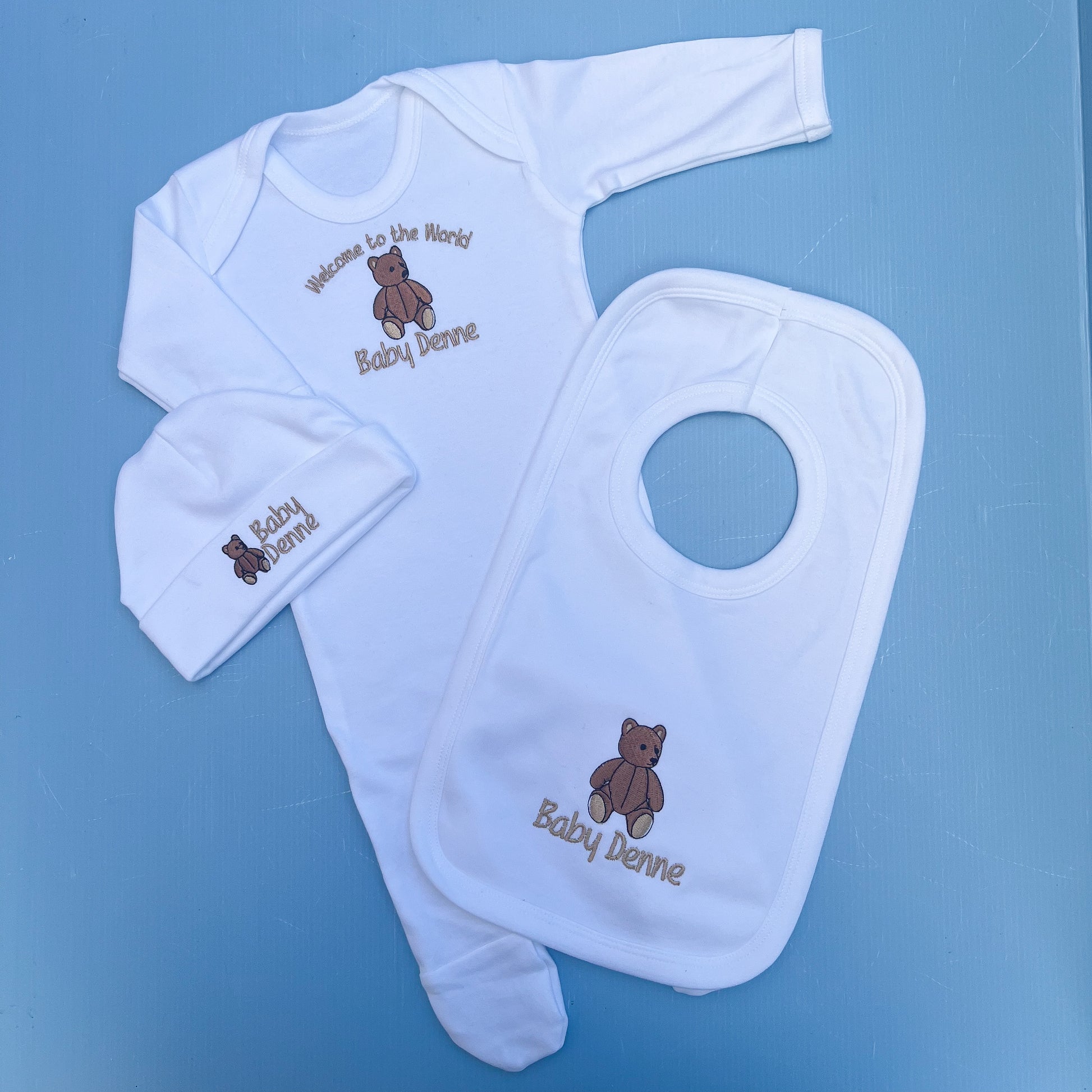 Baby clothing set with bib, hat, and booties on a blue background