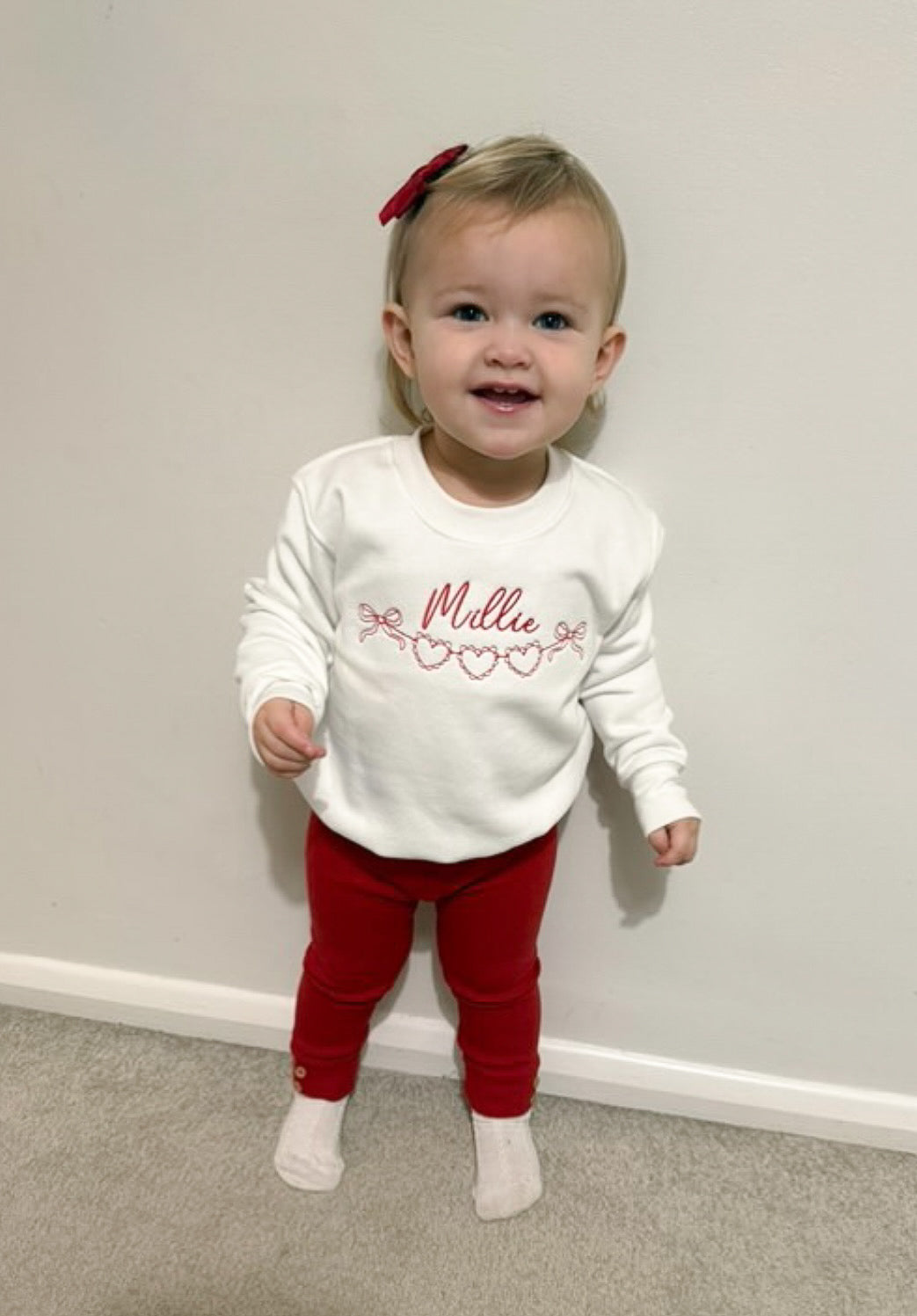 Girl wearing white sweatshirt with red love heart design in embroidery