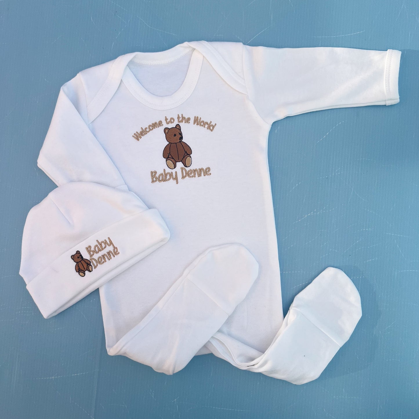 Baby clothing set with long-sleeve onesie, hat, on a blue background