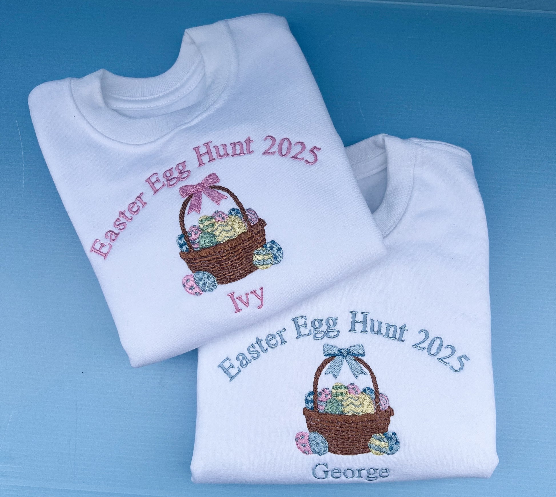 Two folded white sweatshirts with Easter-themed designs and text on a blue background.