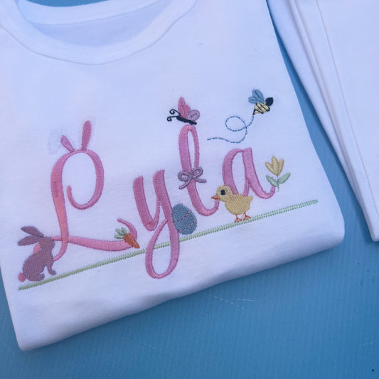 Name Lyla in pink with lots of Easter icons including, bunny rabbit ears, egg, bunny, chick, butter fly and bumble bee 