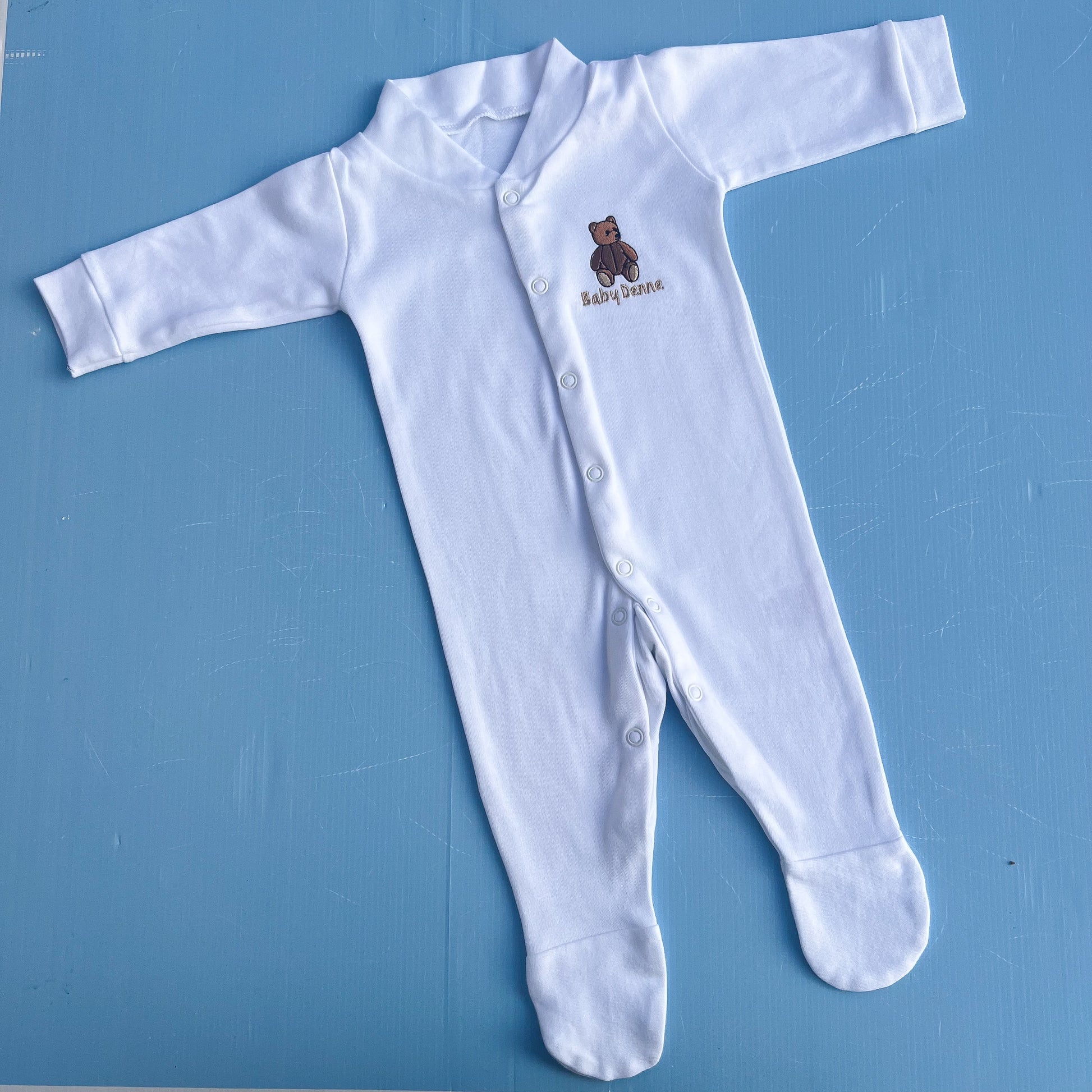White baby onesie with a bear design on a blue surface