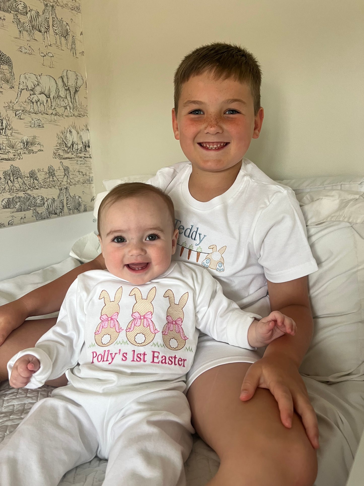 Two children wearing matching Easter-themed outfits on a bed.