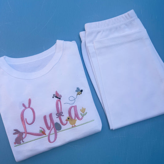 Name Lyla in pink with lots of Easter icons including, bunny rabbit ears, egg, bunny, chick, butter fly and bumble bee 