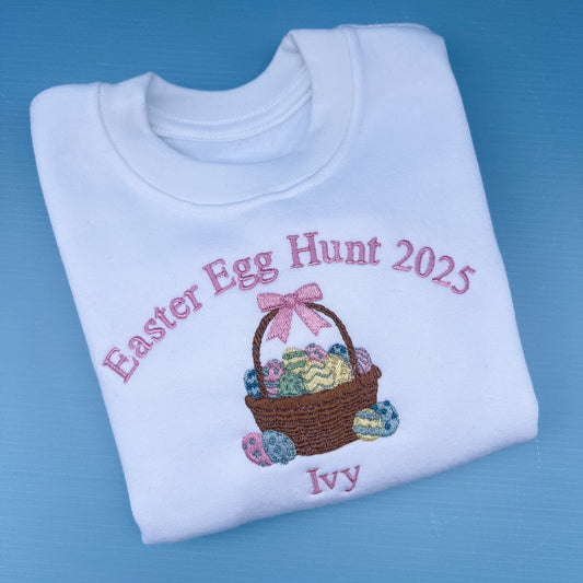 Folded white sweatshirt with Easter Egg Hunt 2025 design on a blue background