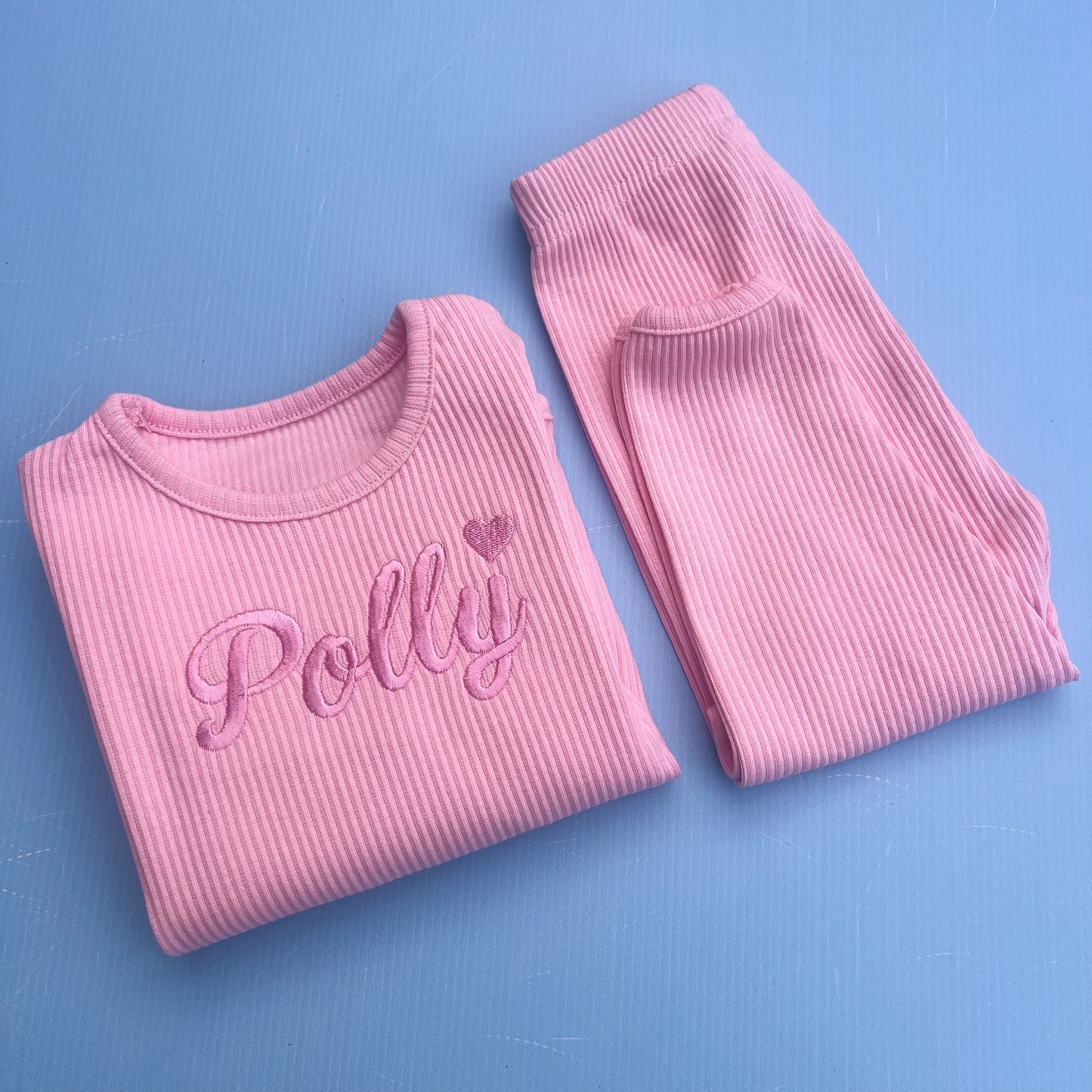 Pink ribbed pajama set with 'Polly' text on a blue background
