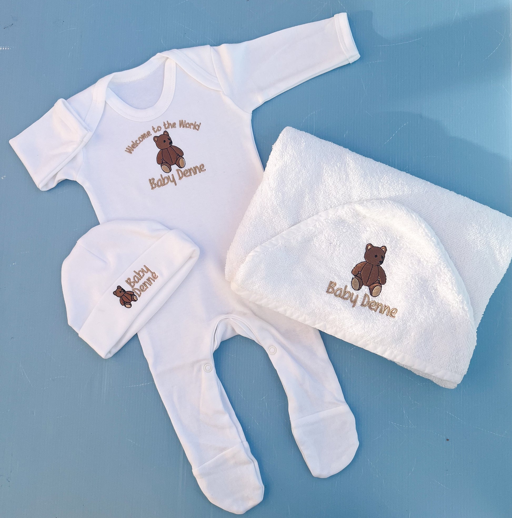 Baby clothing set with embroidered name on a blue background