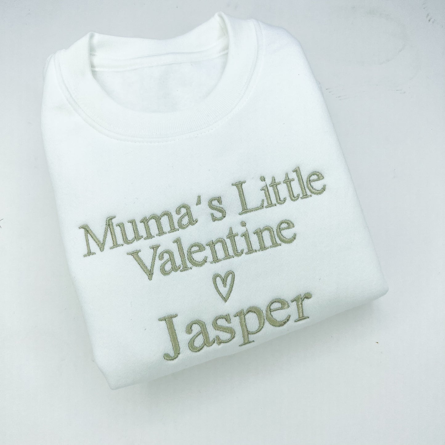 White baby romper with 'Mumma’s Little Valentine Jasper' text on a light gray background