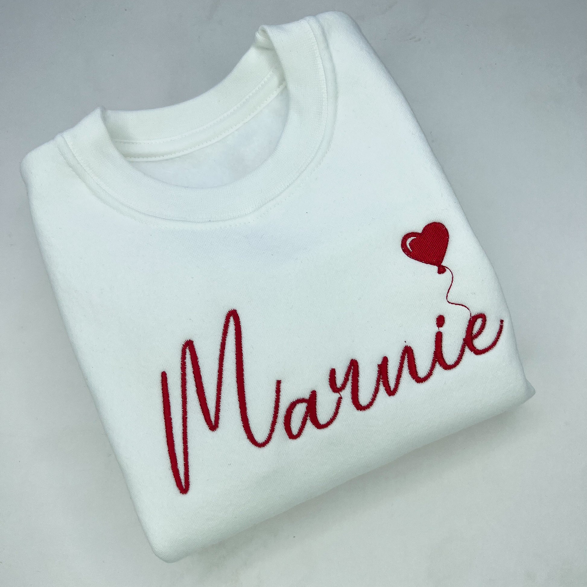 Marnie embroidered with a red heart balloon on a white sweatshirt 