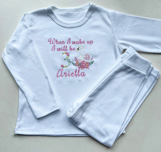 White long-sleeve shirt with embroidered design and text on a light gray background