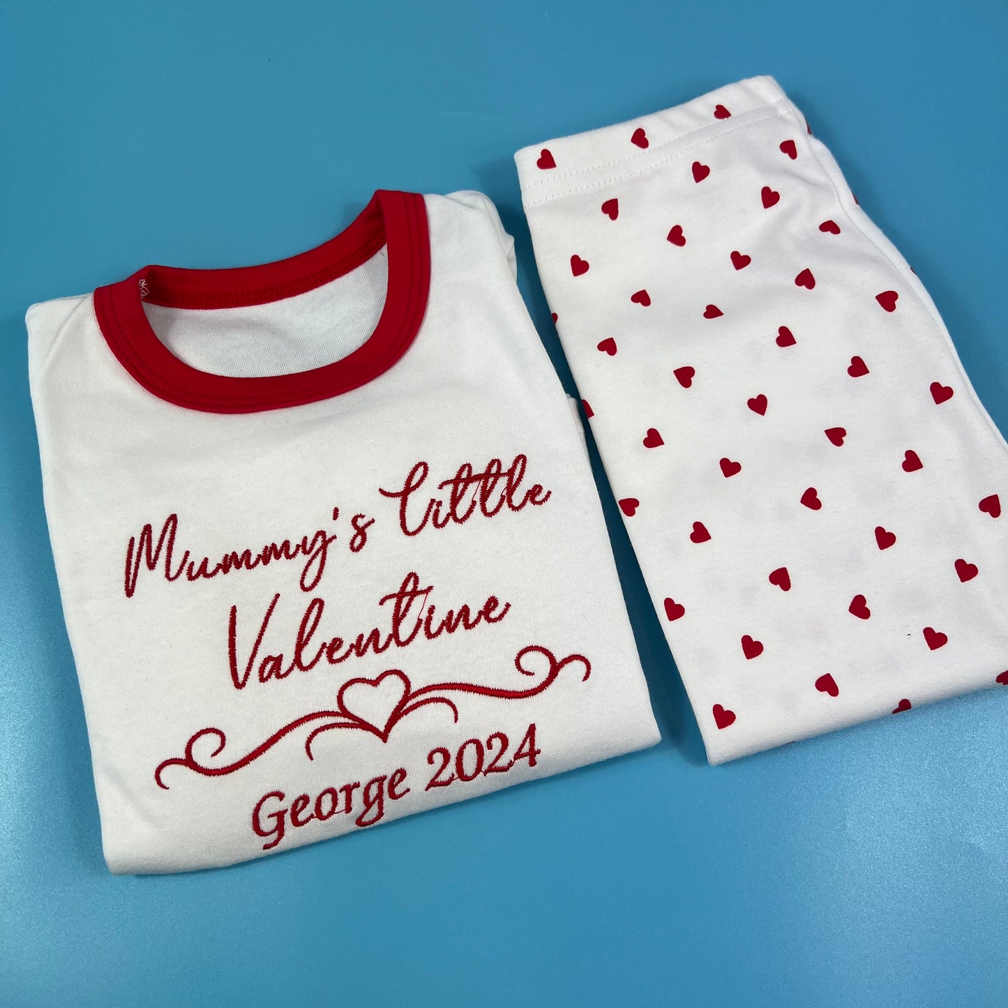 White shirt with red trim and heart-patterned pants on a blue background