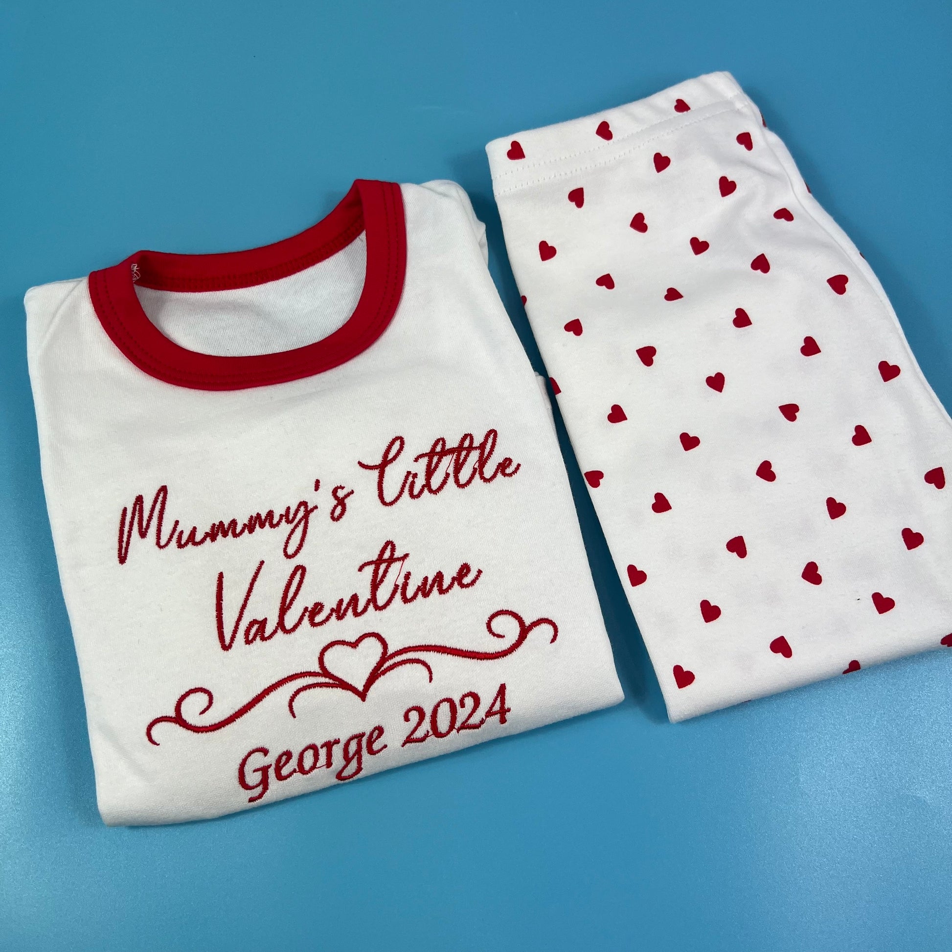 White shirt with red trim and heart-patterned pants on a blue background