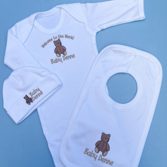 Baby clothing set with bib, hat, and onesie on a blue background