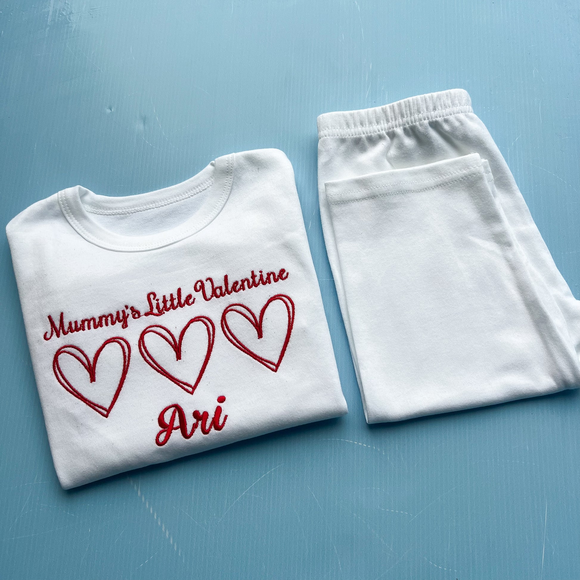 White pyjamas with mummy’s little valentine embroidered on the front with 3 hearts 