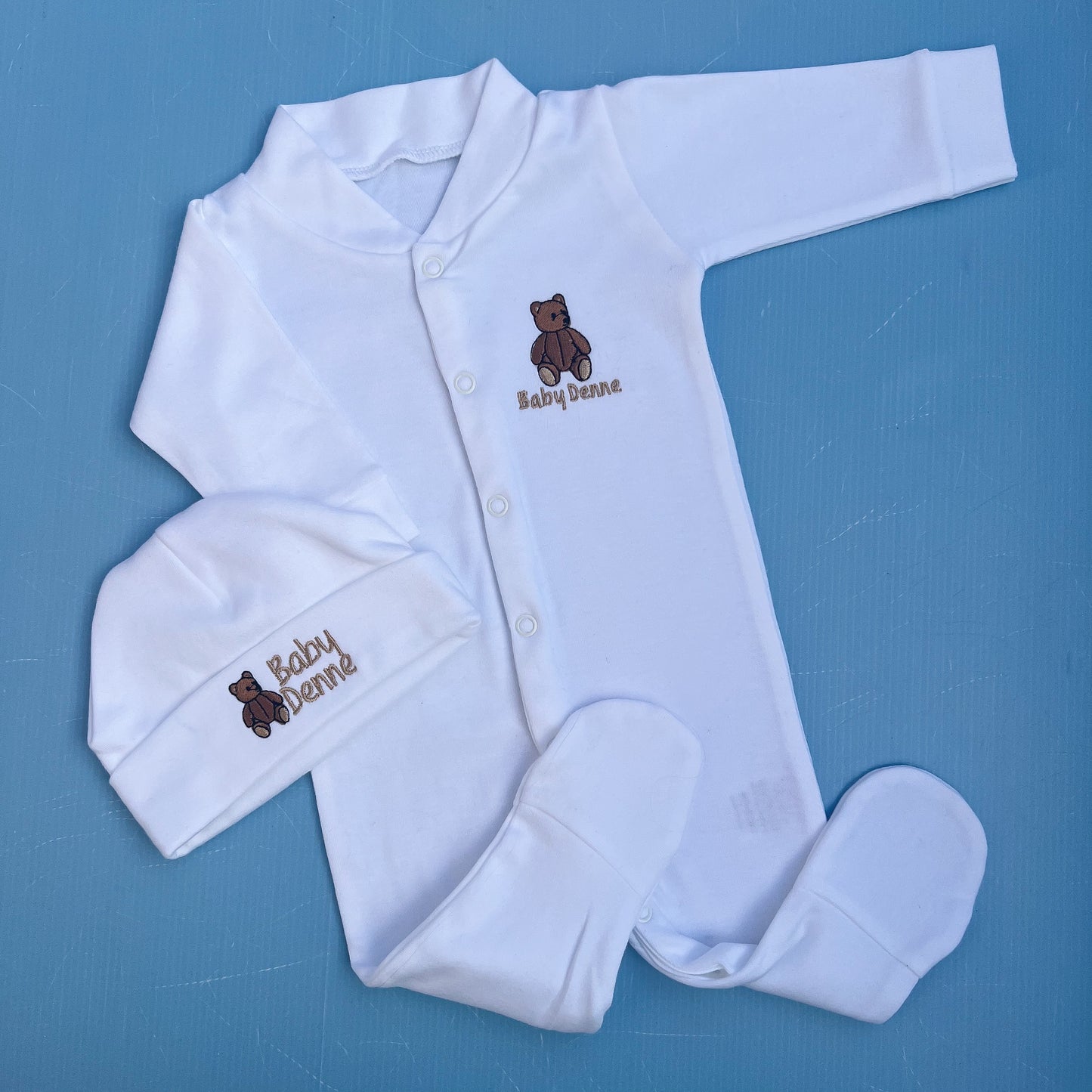 Baby outfit set with white onesie, hat,  on a blue background