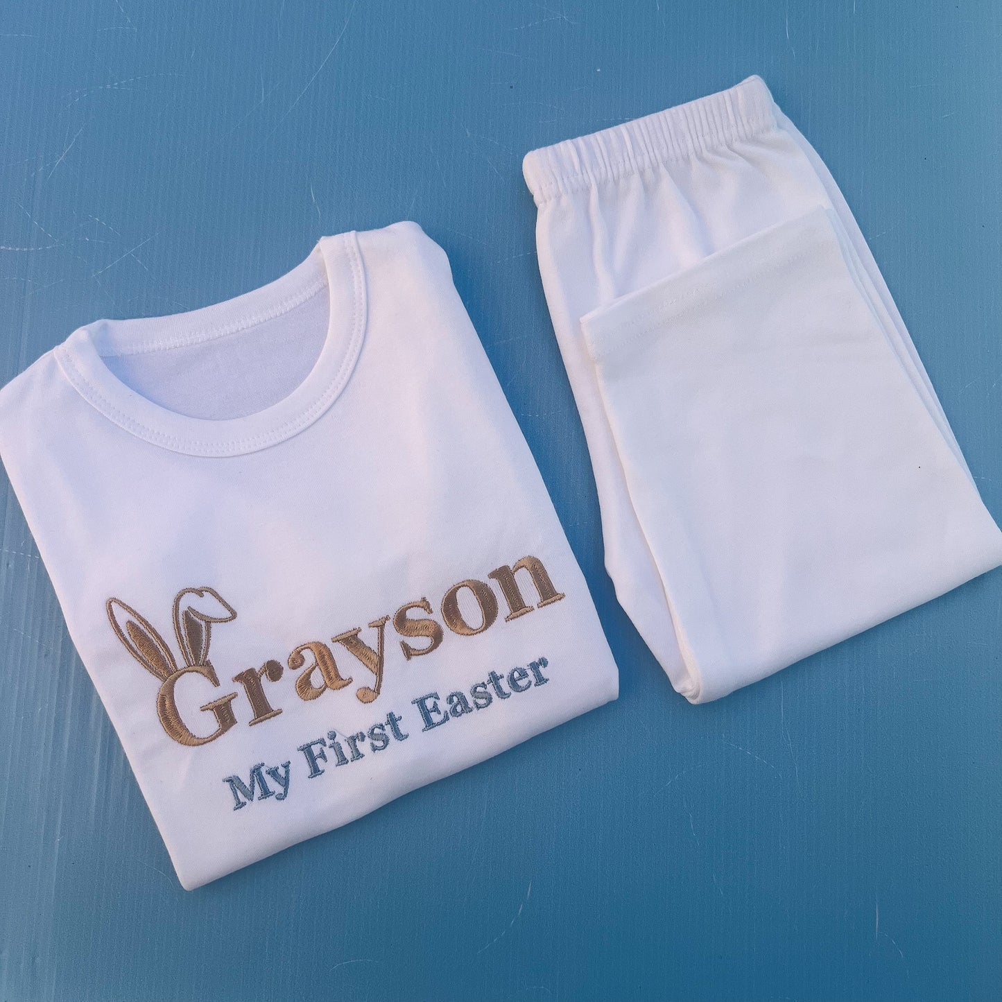 White pyjamas with Grayson first Easter embroidered on with bunny ears 