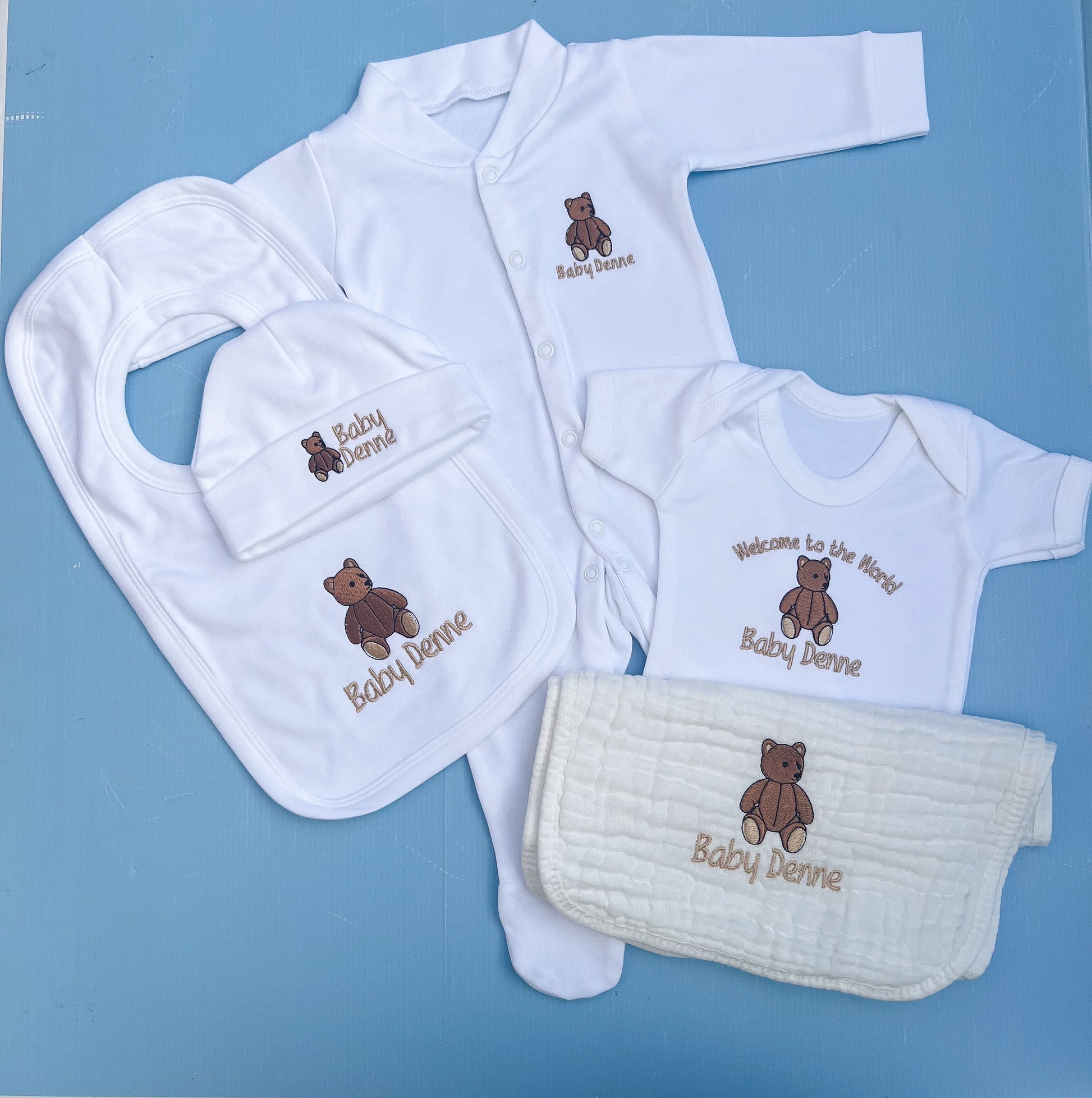 Baby clothing set with bibs, shirts, and burp cloth on a blue background