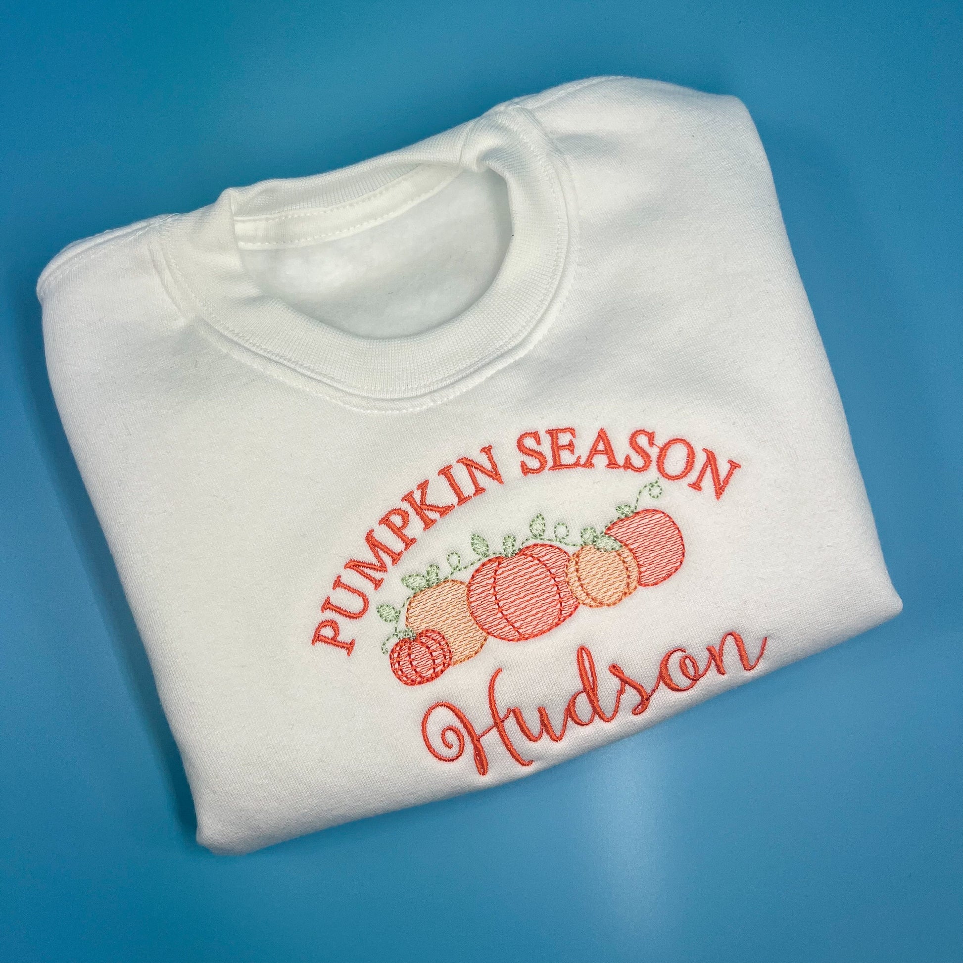 white jumper with pumpkin season in orange embroidery, with 5 pumpkins and childs name